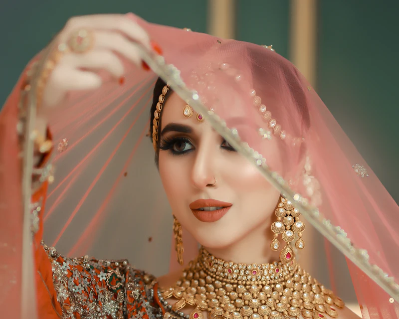 Bride in a peach outfit with a sheer dupatta
